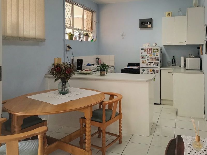 Open plan kitchen and dining area featuring tiled flooring, built-in cabinetry, and a breakfast counter, providing a functional layout for daily living.