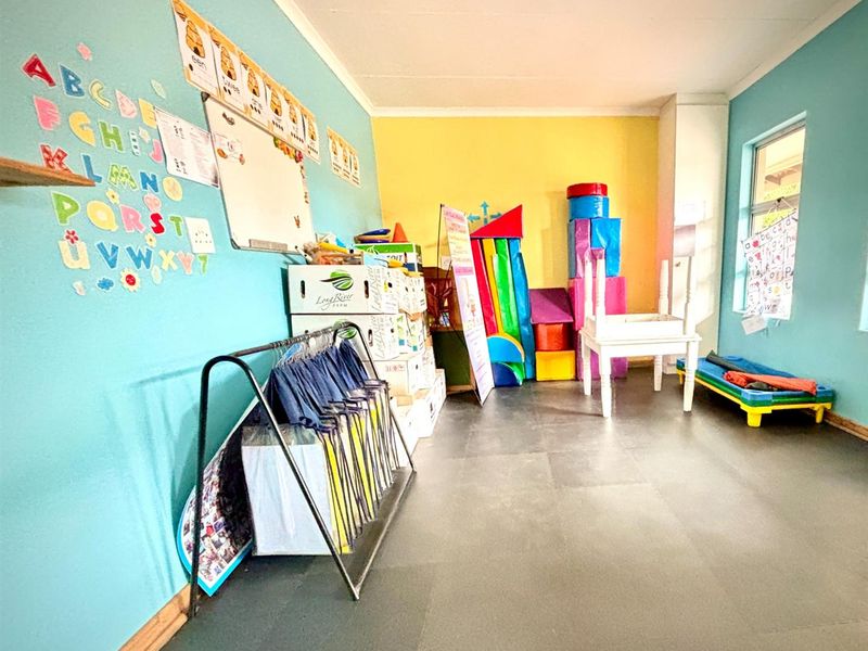 A multi-purpose room currently utilized as a classroom or play area, featuring durable vinyl flooring and brightly painted walls.