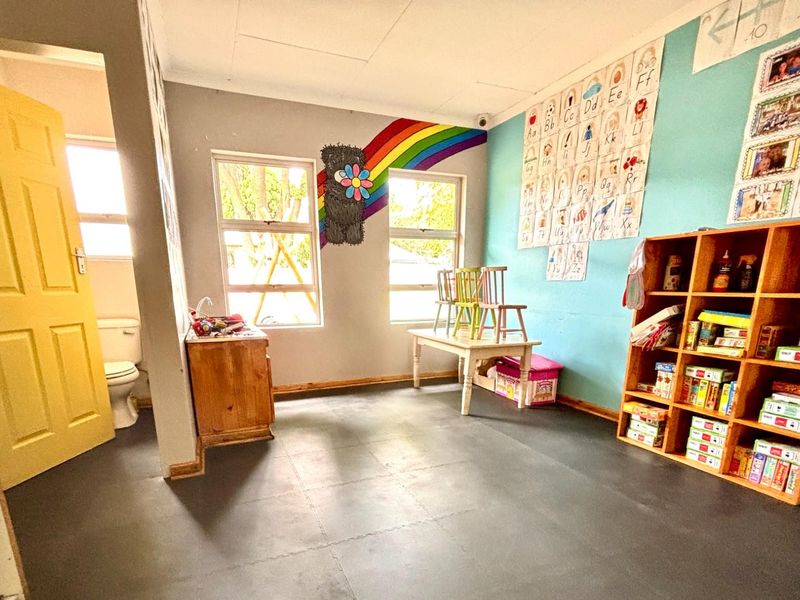 A multi-purpose room featuring durable flooring, built-in shelving, and an adjoining restroom, suitable for use as a classroom, office, or utility space.