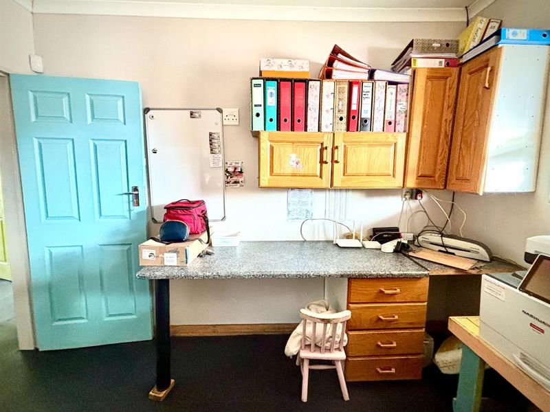 A functional office space featuring built-in wooden cabinetry, a laminate work surface, and a painted internal door.