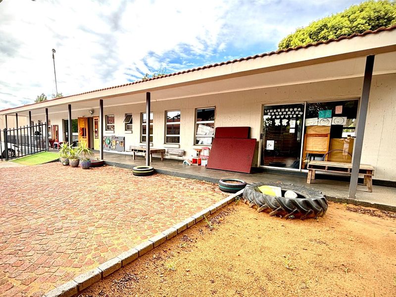 Exterior view of a commercial property featuring a covered patio area, paved ground, and sliding glass door access.