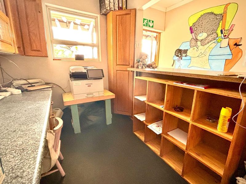 A functional office space featuring built-in wooden cabinetry, laminate countertops, and integrated shelving units, suitable for administrative or workspace use.