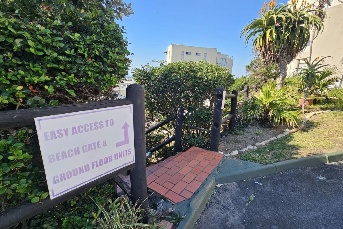 Exterior pathway providing direct access to the beach gate and ground floor apartment units, featuring landscaped garden surroundings.
