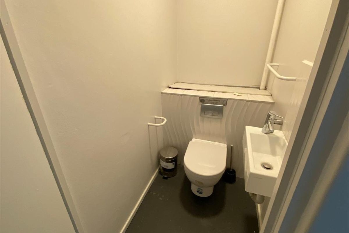 Compact guest bathroom featuring a wall-mounted toilet with concealed cistern and a small wall-mounted basin with chrome fixtures.