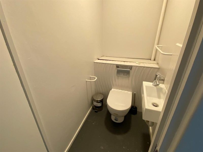 Compact guest bathroom featuring a wall-mounted toilet with concealed cistern and a small wall-mounted basin with chrome fixtures.