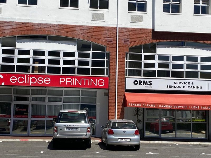 Front elevation of a commercial retail property featuring large glass storefronts, brick detailing, and dedicated parking bays.