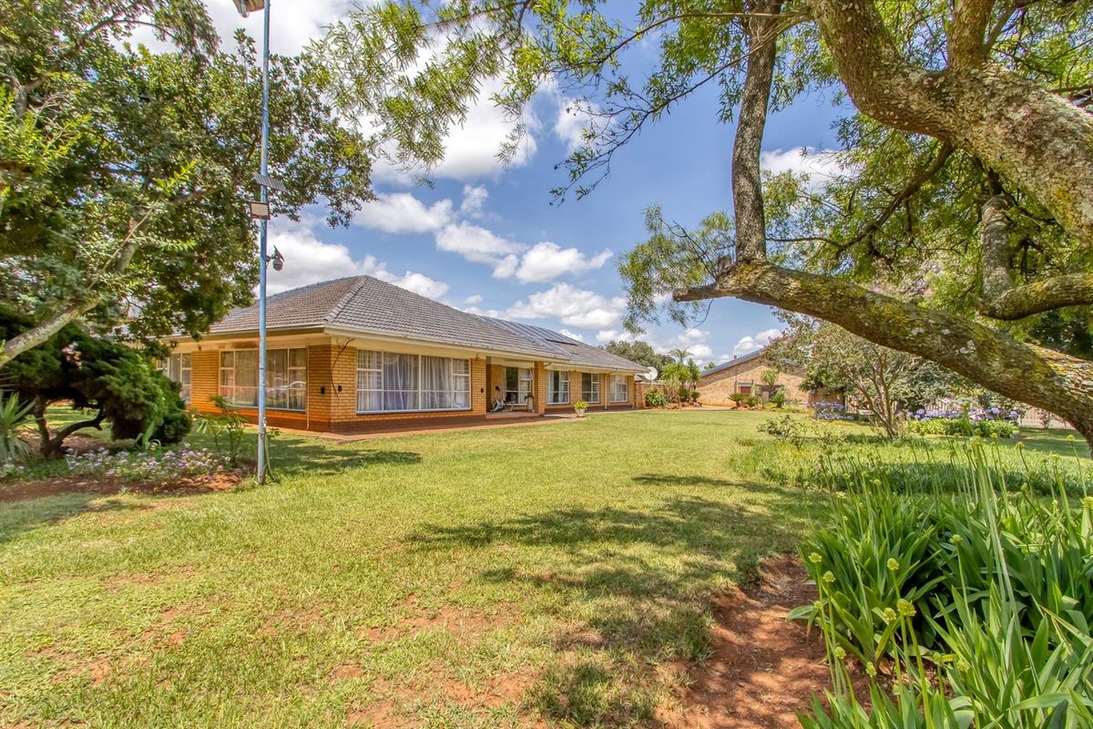 A view of the rear exterior of the property, showcasing the brick facade, tiled roof, and expansive garden area.