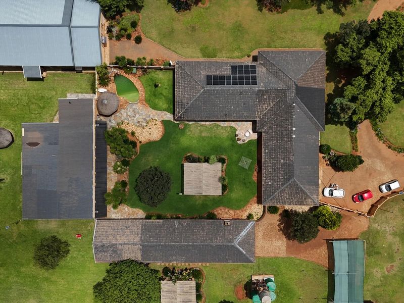 Aerial view of the small holding property featuring multiple buildings, a central garden, swimming pool, and solar panel installation on the main roof.