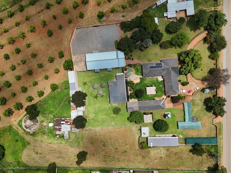Aerial view of a small holding property featuring multiple outbuildings, a main residence, extensive garden areas, and an established orchard.