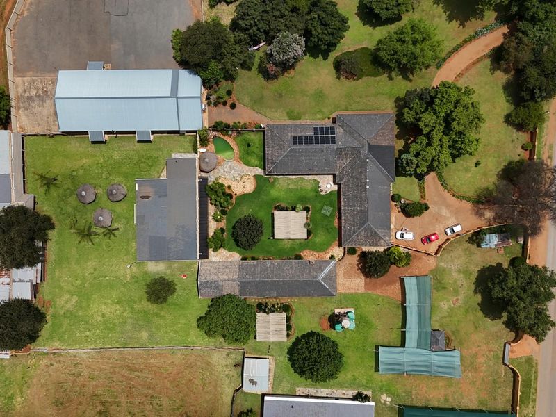 Aerial view of the small holding property, showcasing the main dwelling, outbuildings, landscaped garden, and surrounding grounds.