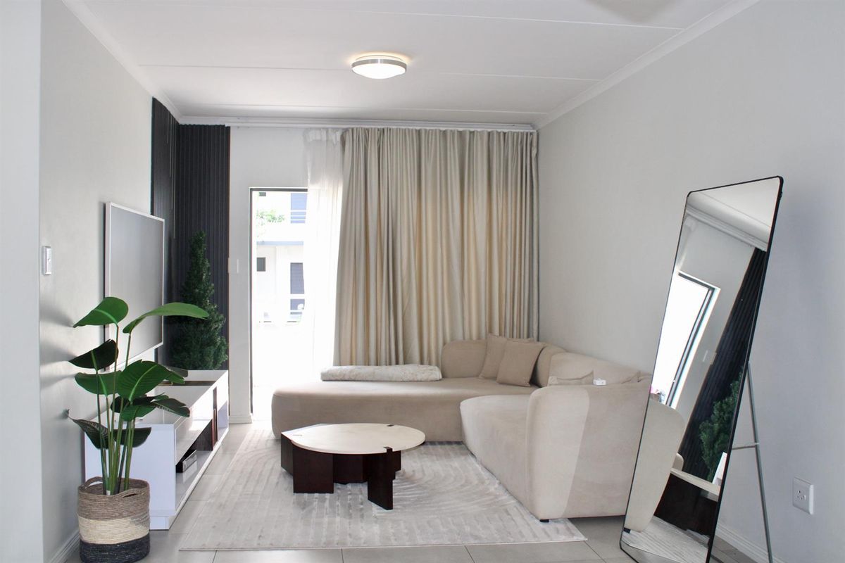 A bright and modern living room featuring tiled flooring, neutral wall finishes, and a sliding door providing access to the exterior.