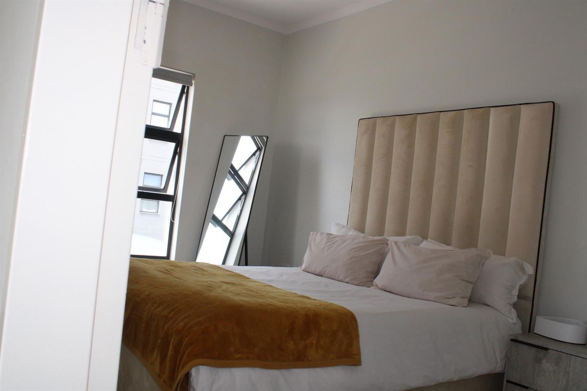 A well-lit bedroom featuring a neutral color palette, modern window frames, and a clean, contemporary aesthetic.