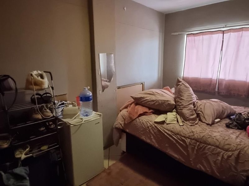 A bedroom featuring a window with curtain rails and visible wall surface wear, requiring cosmetic updates to improve the overall aesthetic.