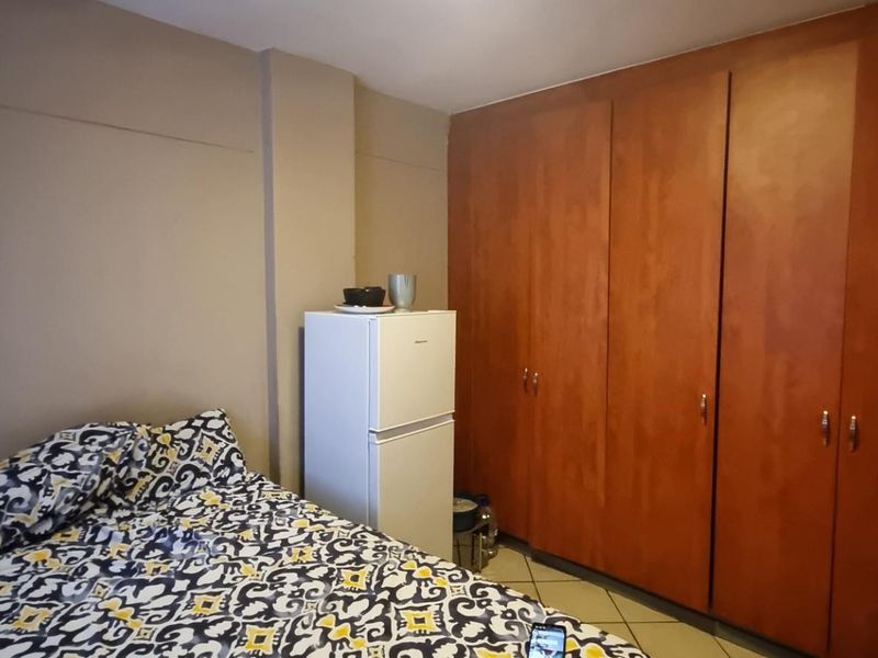 A bedroom featuring a large built-in wooden wardrobe providing ample storage space.