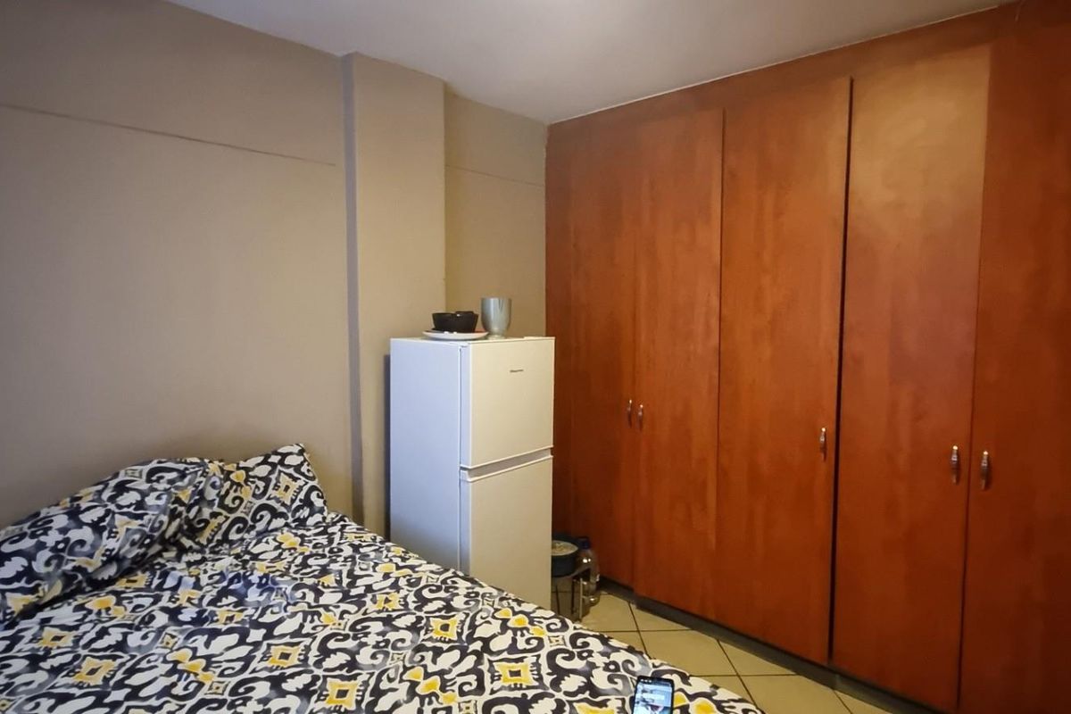 A bedroom featuring a large built-in wooden wardrobe providing ample storage space.
