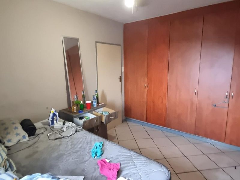 A bedroom featuring built-in wooden cupboards and tiled flooring, offering functional storage space.