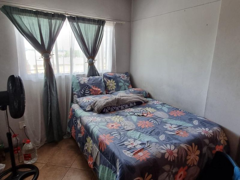 A functional bedroom featuring tiled flooring and a window with curtain fixtures, offering a neutral space ready for personalization.