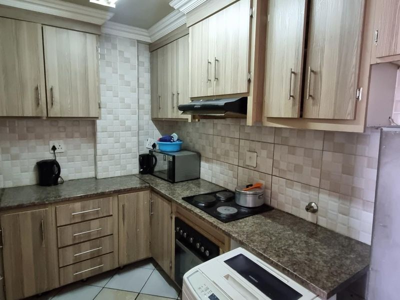 A functional kitchen featuring laminate cabinetry, granite countertops, tiled backsplash, and built-in cooking appliances, offering a practical layout for daily meal preparation.