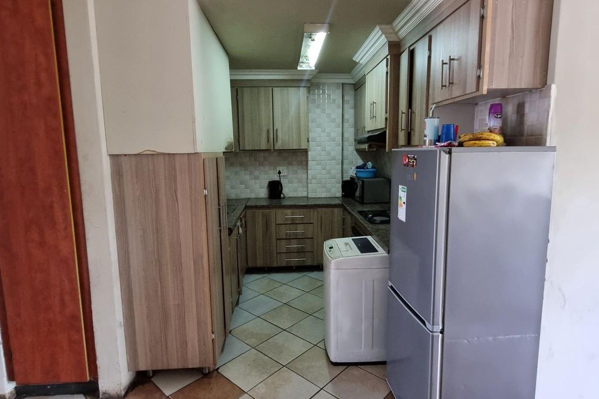 A functional kitchen featuring laminate cabinetry, tiled backsplash, and tiled flooring, offering a practical layout for daily meal preparation.