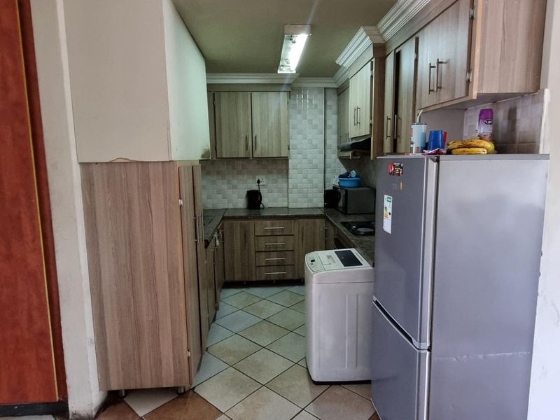 A functional kitchen featuring laminate cabinetry, tiled backsplash, and tiled flooring, offering a practical layout for daily meal preparation.