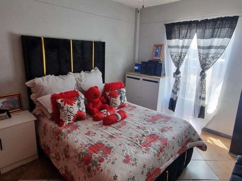A functional bedroom featuring tiled flooring and a window with curtains, providing a simple and practical living space.