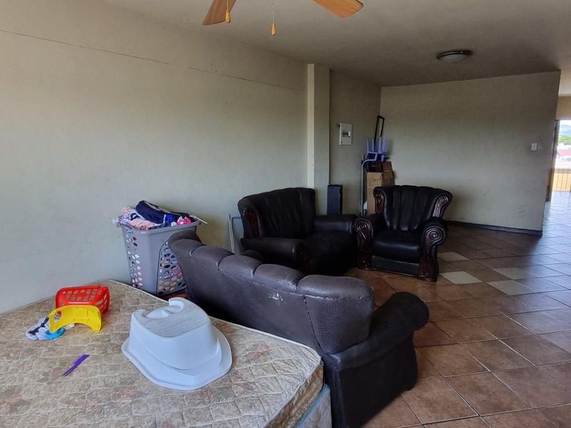 A spacious living area featuring ceramic floor tiles, a ceiling fan, and neutral wall finishes, offering a blank canvas for potential interior updates.