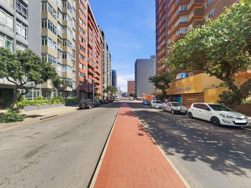 A street-level view of the urban neighborhood surrounding the apartment building, featuring paved sidewalks and multi-story residential architecture.