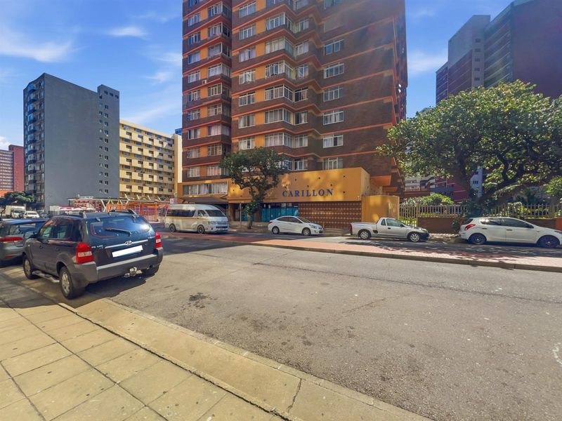 Street view of the Carillon apartment building, showcasing its multi-story brick facade and ground-level entrance area in an urban setting.
