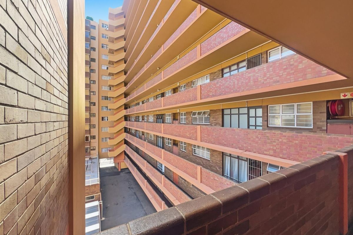 View from a balcony overlooking the exterior facade and brick architecture of a multi-story apartment complex.