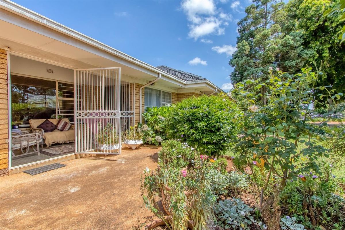 A rear patio area featuring a paved terrace, security gate, and direct access to the garden through large sliding glass doors.