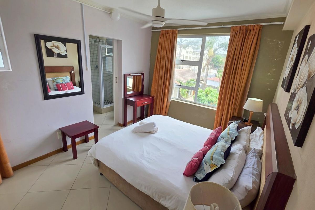 A bedroom featuring tiled flooring, a ceiling fan, and an en-suite bathroom with a shower enclosure.