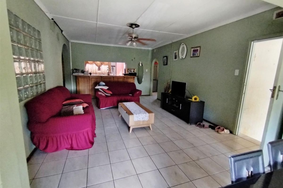 Spacious living room featuring tiled flooring, a ceiling fan, and a built-in serving counter connecting to the kitchen area.