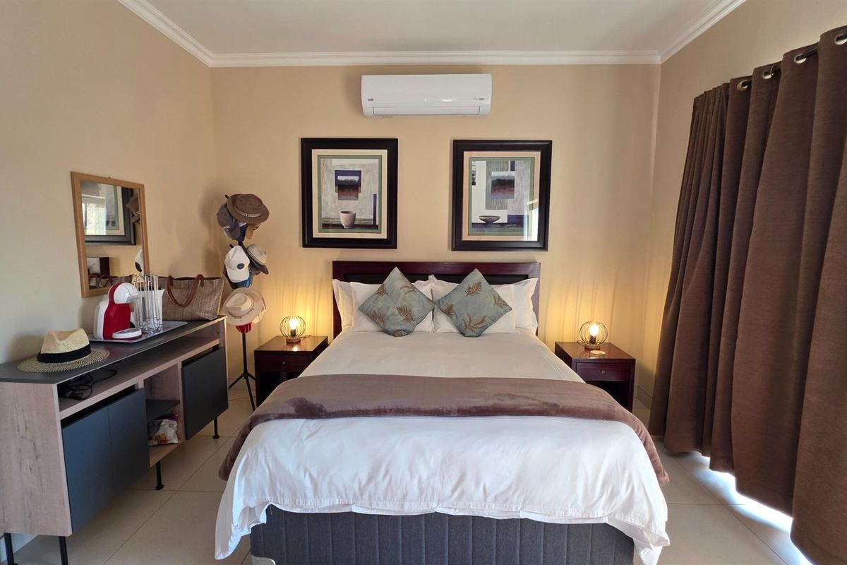 A well-maintained bedroom featuring tiled flooring, crown molding, and a wall-mounted split-system air conditioning unit.