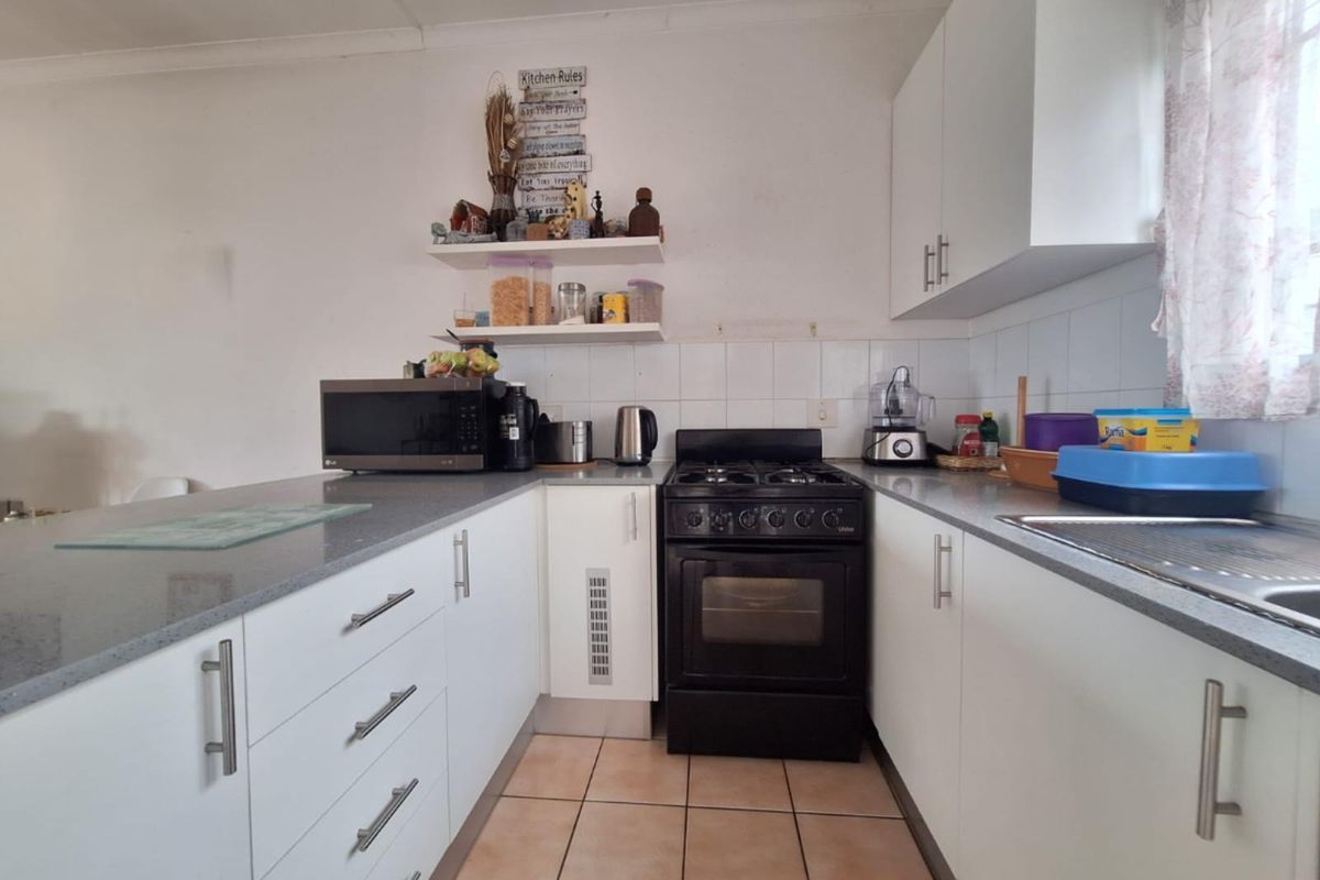 A functional kitchen featuring white cabinetry, grey countertops, tiled flooring, and a built-in gas stove with an oven.