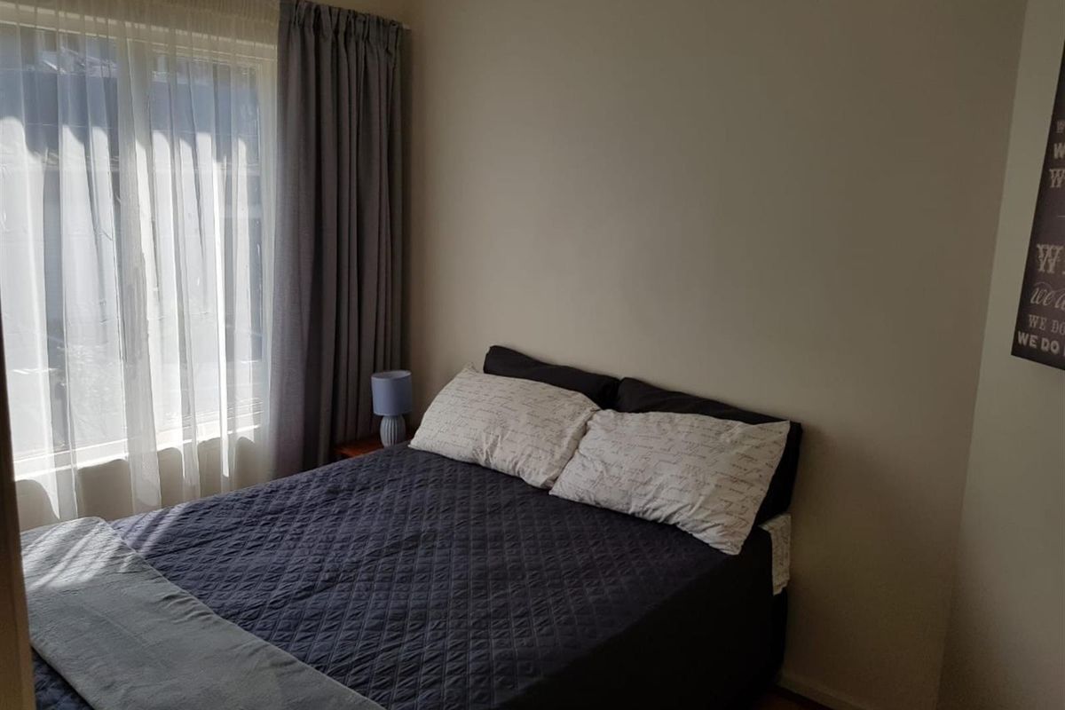 A bedroom featuring neutral wall finishes and a window with curtain treatments, providing a functional and comfortable sleeping space.
