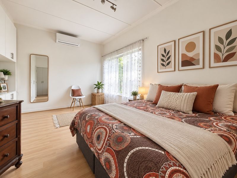 A well-maintained bedroom featuring laminate flooring, built-in cabinetry, and a wall-mounted split-system air conditioner.