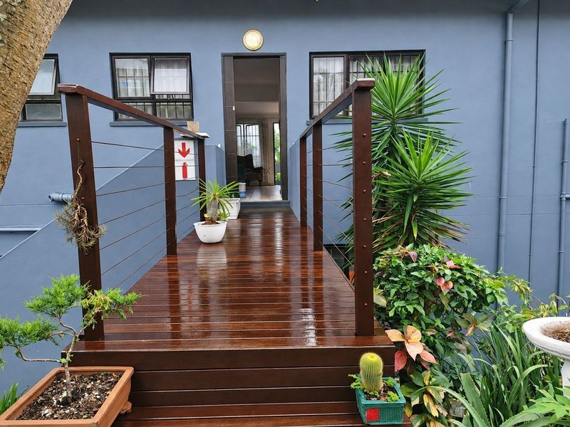 An elevated timber walkway leading to the main entrance, featuring modern wire balustrades and well-maintained exterior finishes.