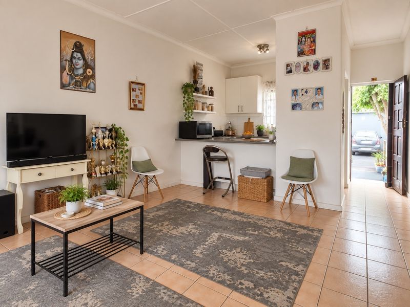 Open plan living area featuring tiled flooring and a breakfast bar connecting to the kitchen, with direct access to the exterior entrance.