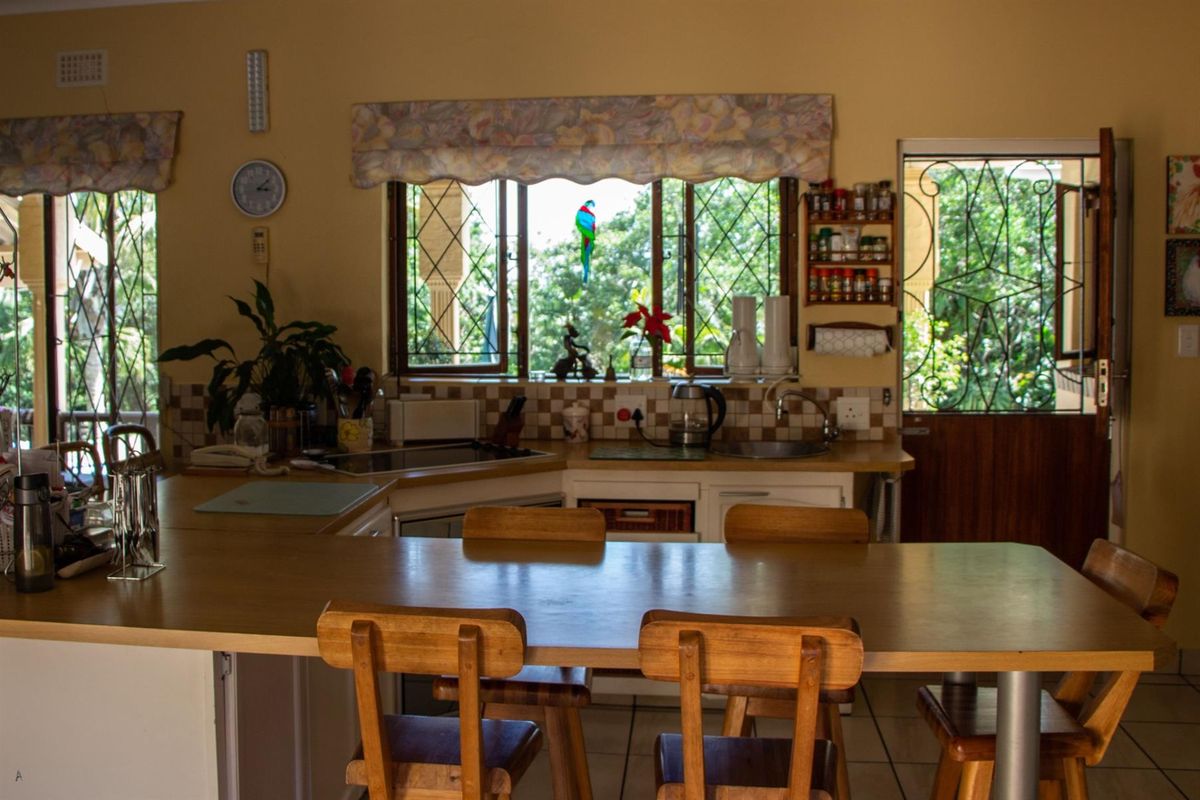 A functional kitchen featuring a breakfast bar, tiled backsplash, and direct access to the outdoor area through a security gate.