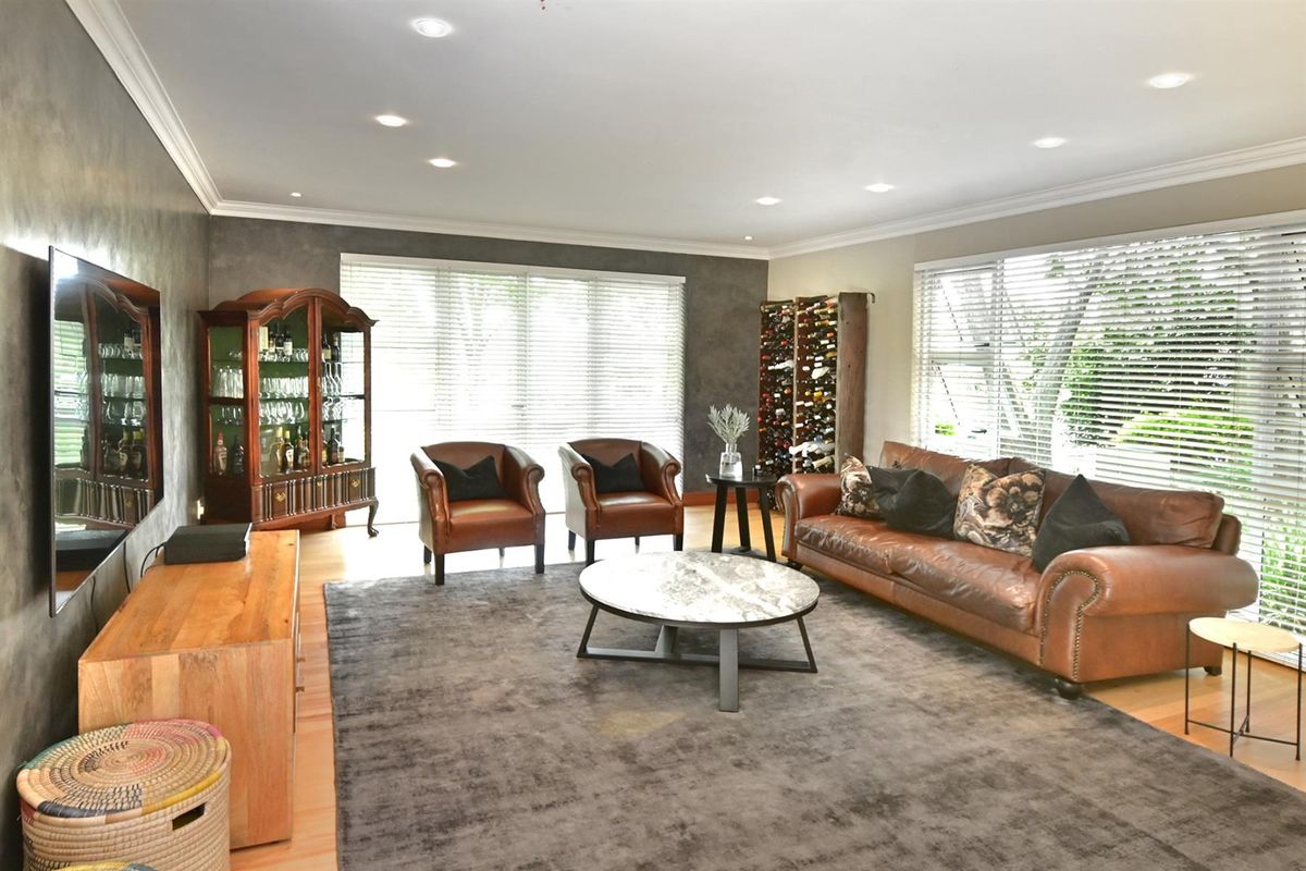Spacious living room featuring recessed downlighting, timber flooring, and large windows with fitted blinds, creating a bright and comfortable atmosphere.