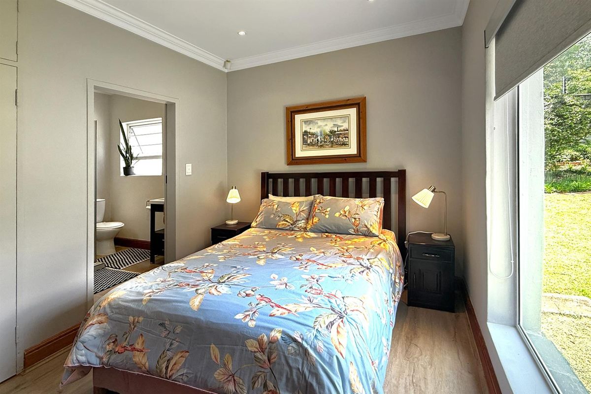 A well-maintained bedroom featuring neutral walls, crown molding, and large windows, with an adjoining en-suite bathroom.