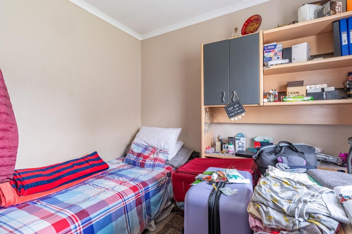 A compact bedroom featuring neutral wall tones and built-in shelving unit.