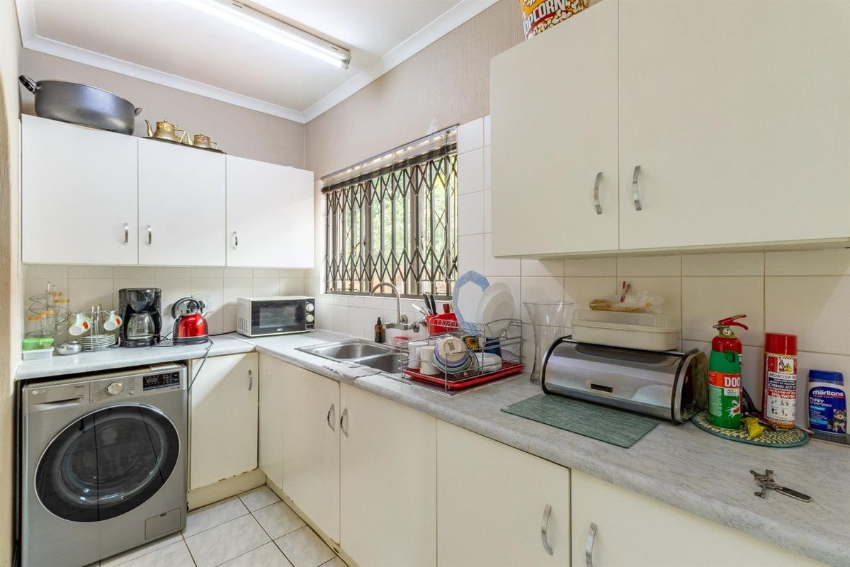 Functional kitchen featuring white cabinetry, laminate countertops, stainless steel sink, and integrated laundry plumbing for a washing machine.
