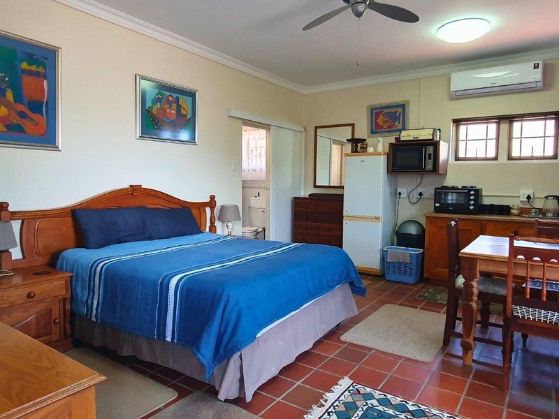 Spacious bedroom featuring terracotta tile flooring, a ceiling fan, and a split-system air conditioner, with an adjoining en-suite bathroom.