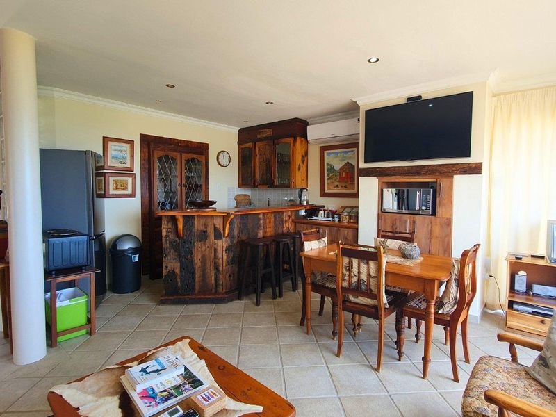 Open-plan living area featuring a rustic built-in bar, tiled flooring, and recessed lighting, creating a functional space for entertaining and daily living.