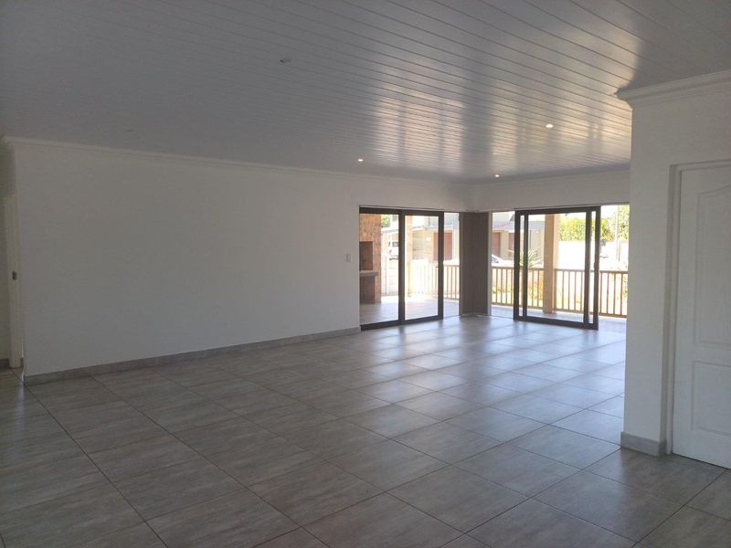 Spacious open-plan living area featuring large sliding glass doors that open onto a covered patio with a built-in brick braai.