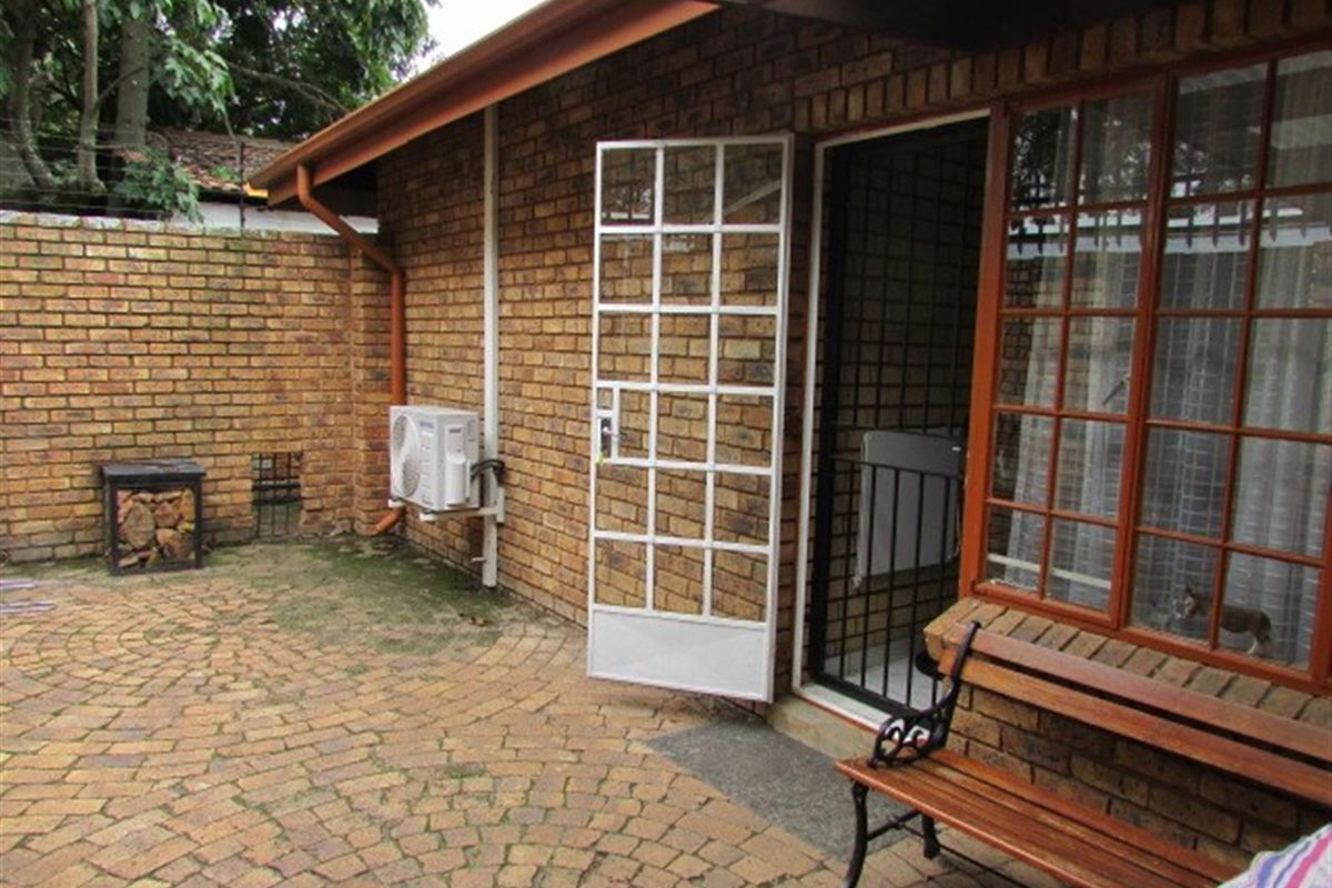 A private rear courtyard featuring facebrick walls, brick paving, and a timber pergola, providing a functional outdoor space with direct access to the home.