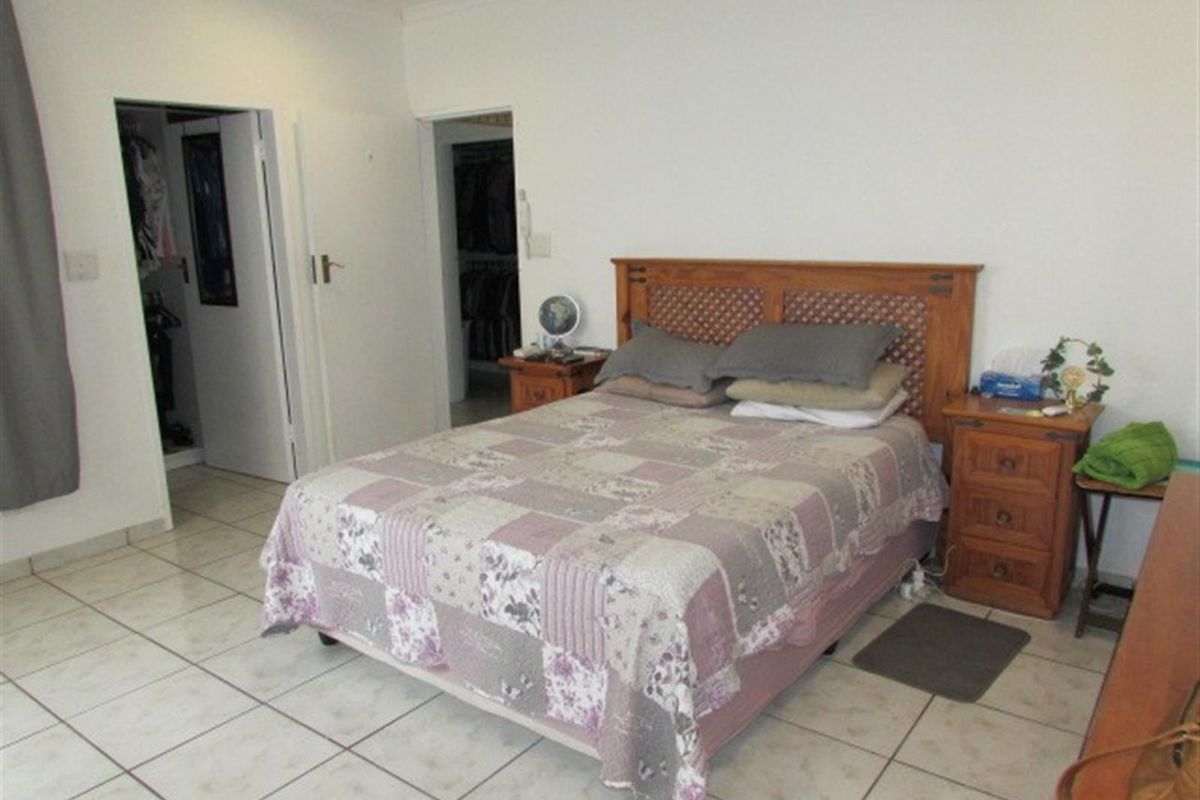 A functional bedroom featuring tiled flooring, recessed lighting, and direct access to a walk-in closet area.