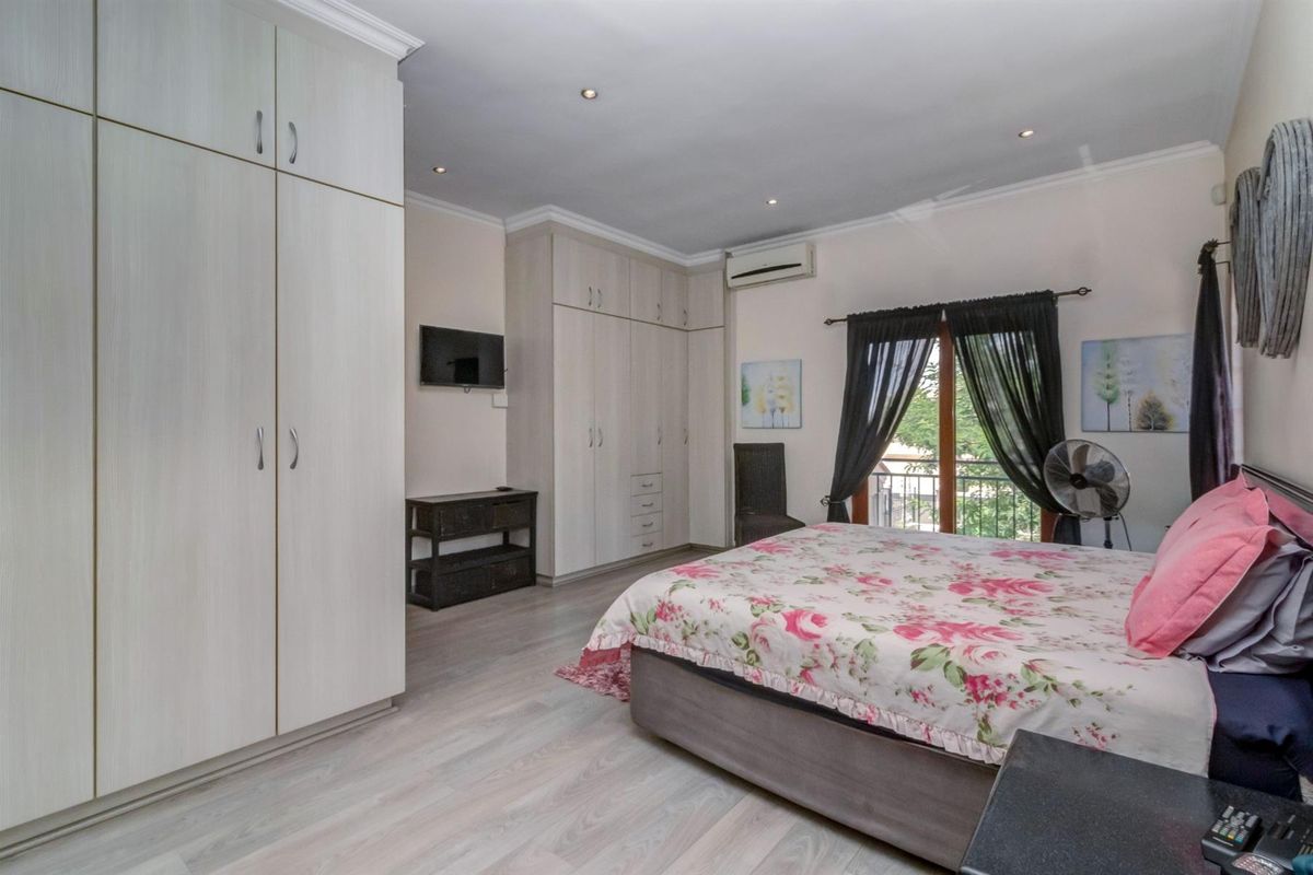 Spacious bedroom featuring light-toned laminate flooring, extensive built-in cabinetry, recessed lighting, and direct access to a private balcony via sliding doors.