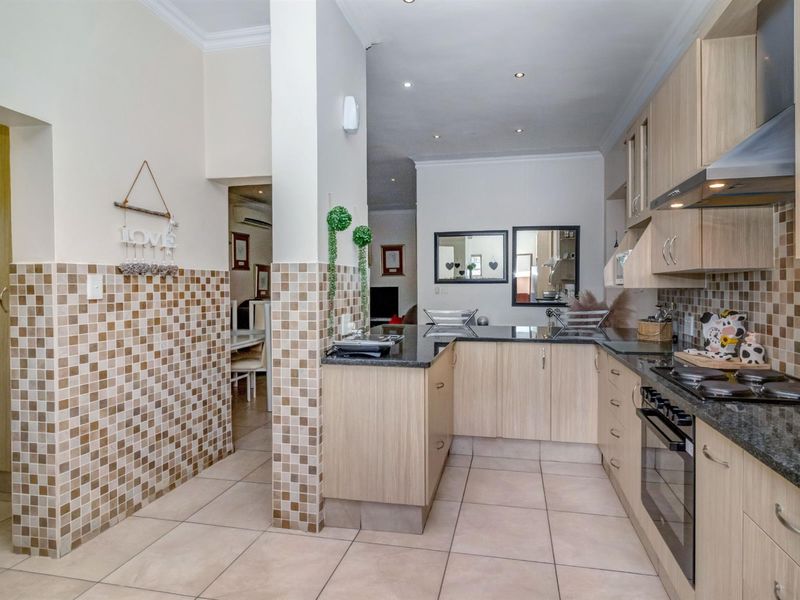 A functional kitchen featuring light wood cabinetry, granite countertops, a built-in oven, gas hob, and decorative mosaic wall tiling.